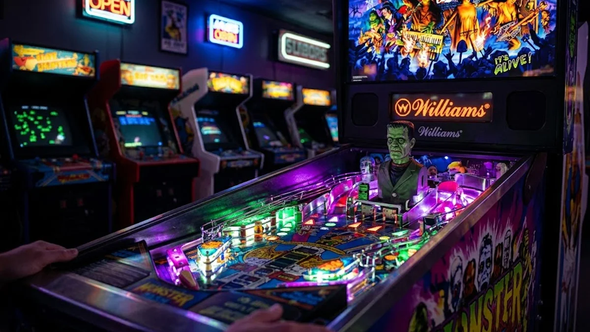 Vista detalhada do playfield da máquina de pinball Monster Bash, destacando o boneco do Frankenstein e as rampas coloridas.