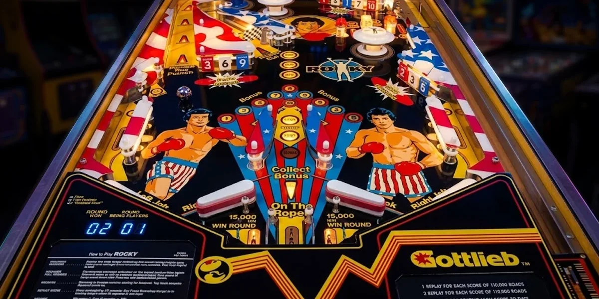 maquina-de-pinball-rocky-gottlieb-1982-playfield Máquina de pinball Rocky (Gottlieb, 1982) exibindo o playfield detalhado com Sylvester Stallone no clássico de fliperama.