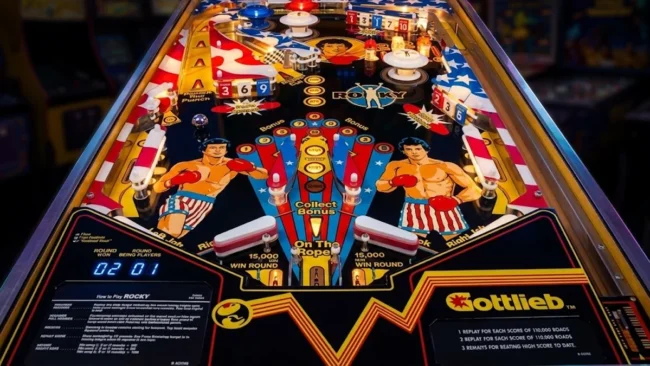 maquina-de-pinball-rocky-gottlieb-1982-playfield Máquina de pinball Rocky (Gottlieb, 1982) exibindo o playfield detalhado com Sylvester Stallone no clássico de fliperama.